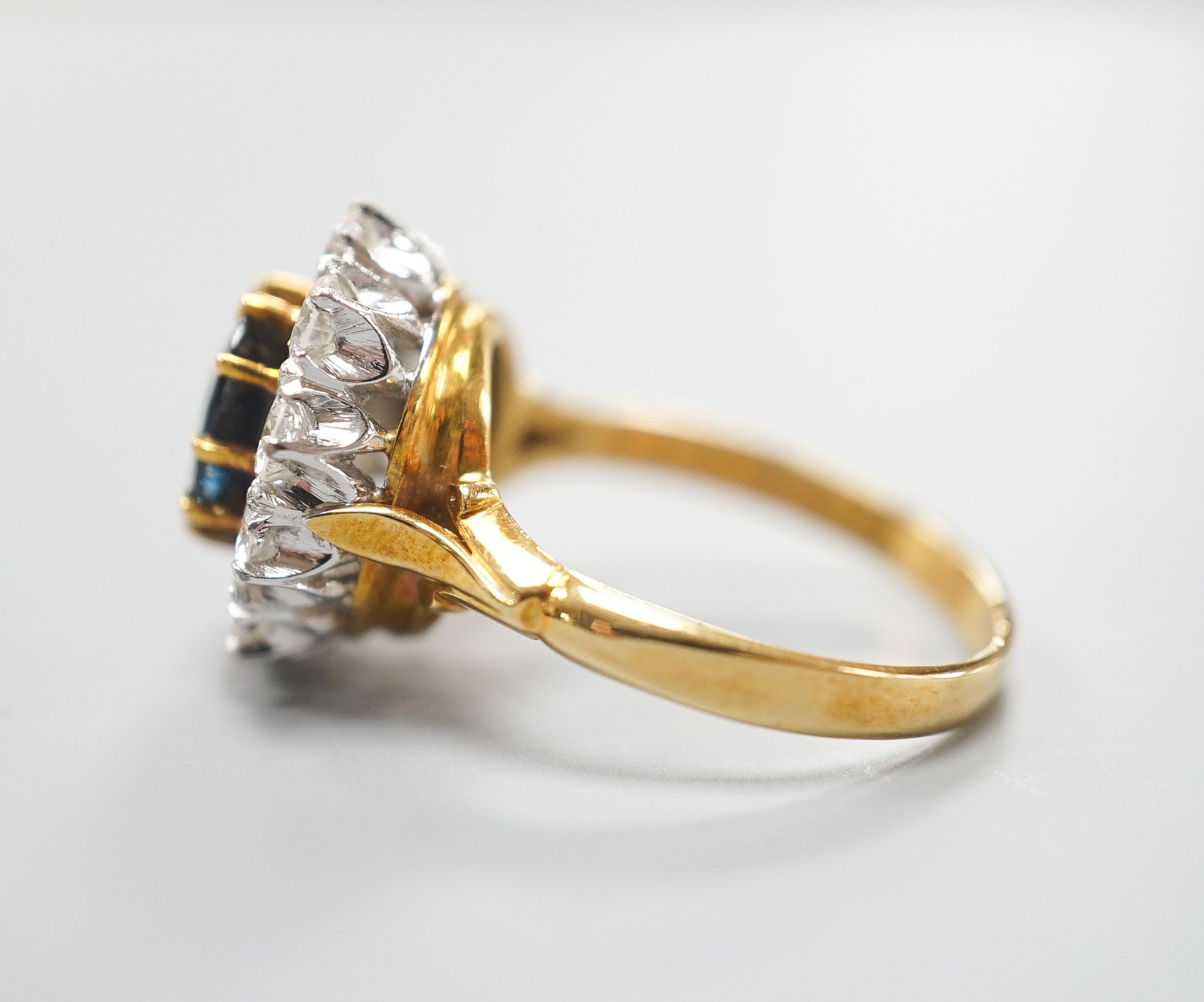 A modern 18ct gold, sapphire and diamond set oval cluster ring, size P/Q, gross weight 6.2 grams.